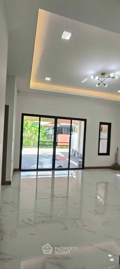 Spacious modern living room with large sliding glass doors and elegant ceiling lights.