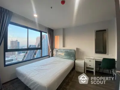 Bright and airy bedroom with large window offering city views, modern furnishings, and a cozy ambiance in a high-rise apartment.