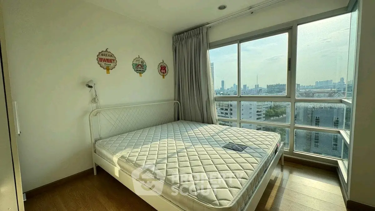 Bright bedroom with large windows and city view, featuring a cozy bed and modern decor.