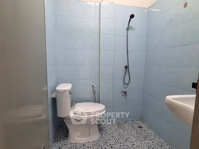 Spacious bathroom with blue tiled walls and modern fixtures in a real estate property.
