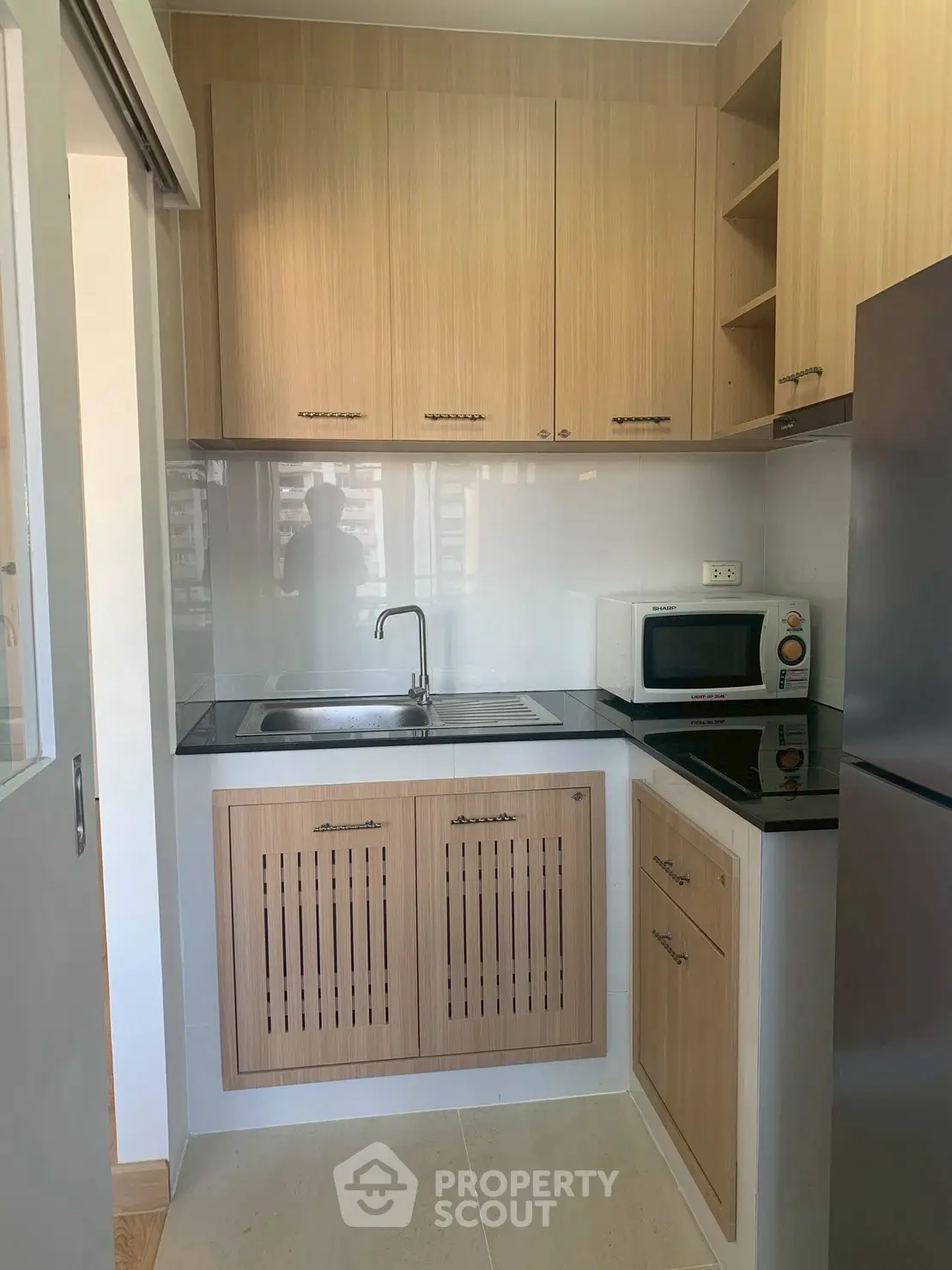 Modern compact kitchen with wooden cabinets and sleek appliances