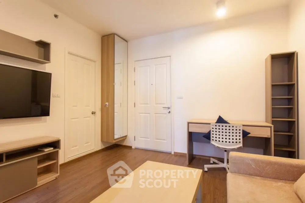 Modern minimalist living room with ample natural light, featuring sleek built-in shelves, a cozy sofa, and a wall-mounted flat-screen TV, perfect for urban living.