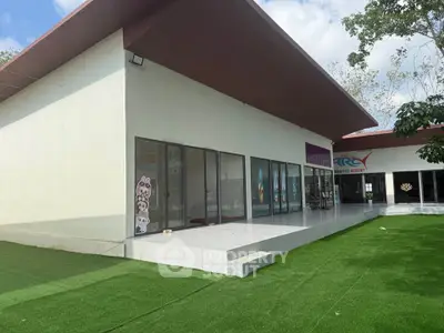 Modern commercial building with large glass windows and green artificial turf exterior.