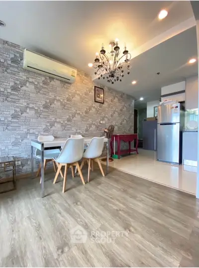 Modern dining area with stylish chandelier and open kitchen layout in a contemporary apartment.