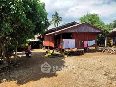 Charming rustic wooden house with lush greenery and spacious outdoor area, perfect for serene living.