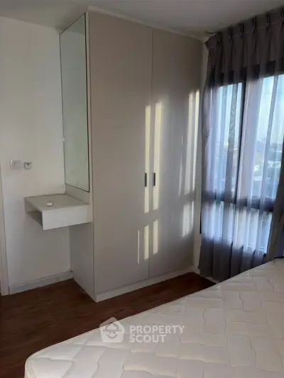 Cozy bedroom with natural light, featuring a built-in wardrobe and a comfortable mattress.