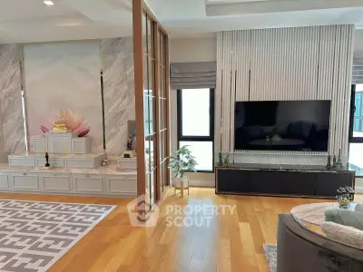 Luxurious living room with modern decor and large TV, featuring elegant wood flooring and stylish wall paneling.