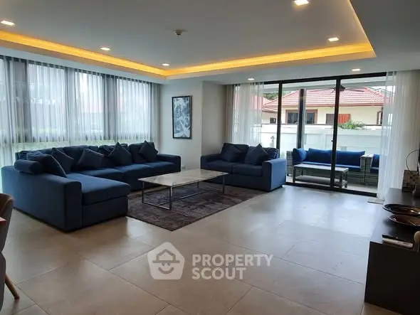 Spacious modern living room with large windows and stylish blue sofas