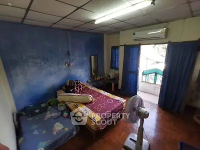 Cozy bedroom with blue accent wall and balcony access, featuring a fan and air conditioning for comfort.