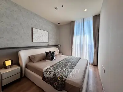 Luxurious bedroom with elegant decor and large window offering natural light.