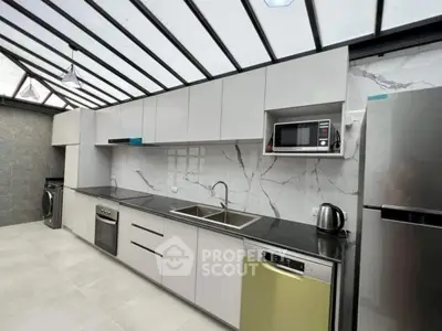 Modern kitchen with sleek cabinetry, stainless steel appliances, and marble backsplash under a glass ceiling.