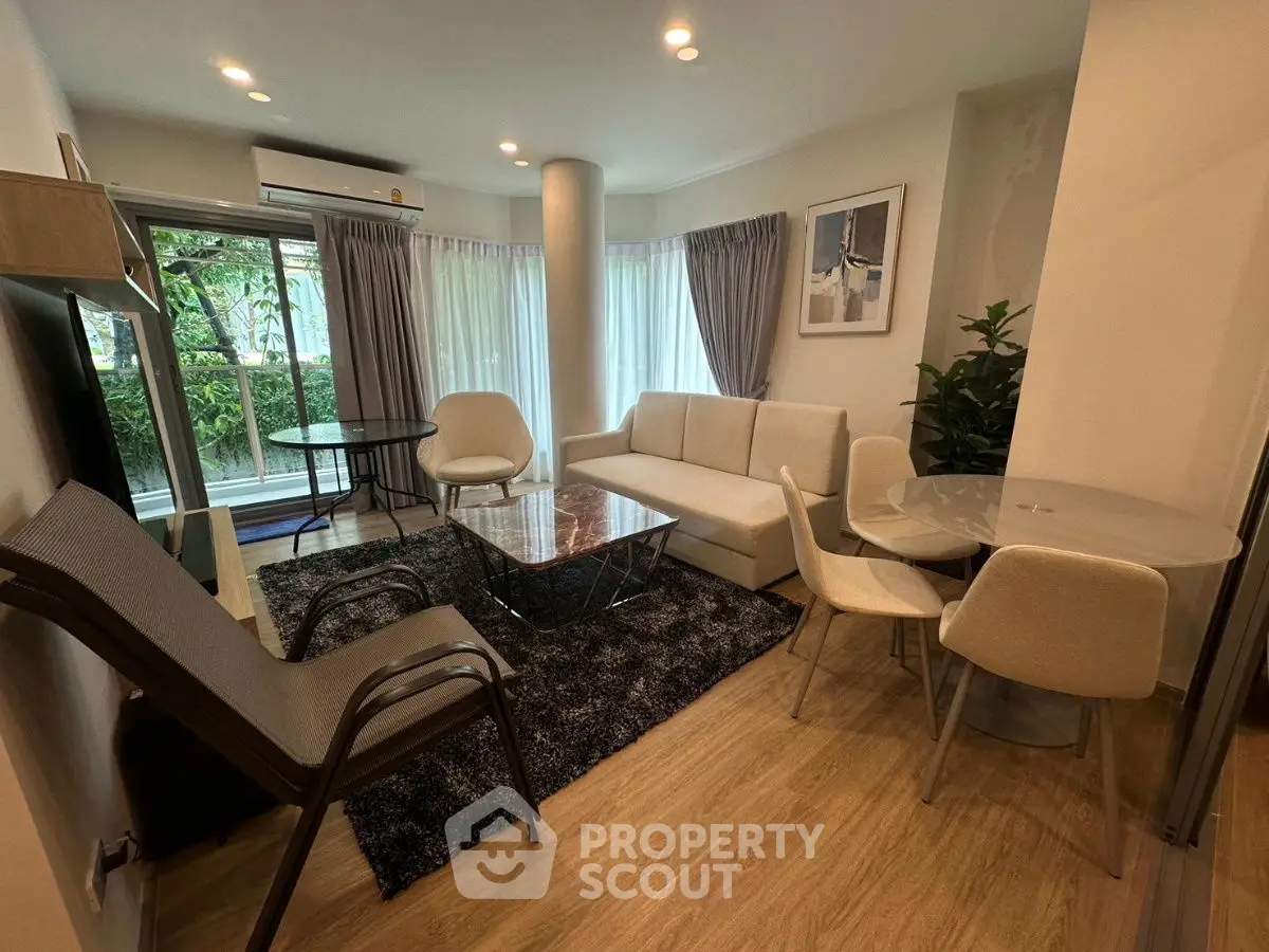 Modern living room with stylish furniture and large windows overlooking greenery.