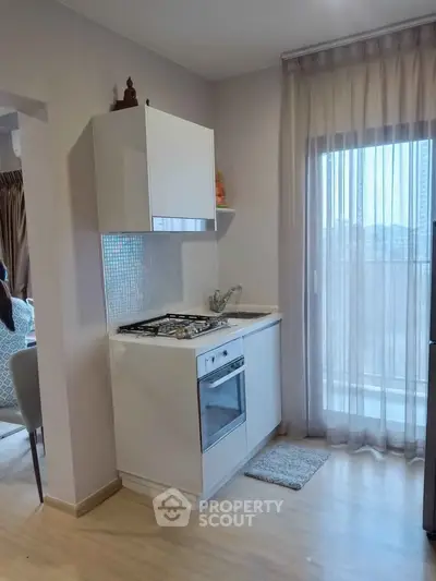 Modern kitchen with gas stove and oven, featuring sleek cabinetry and a bright window view.