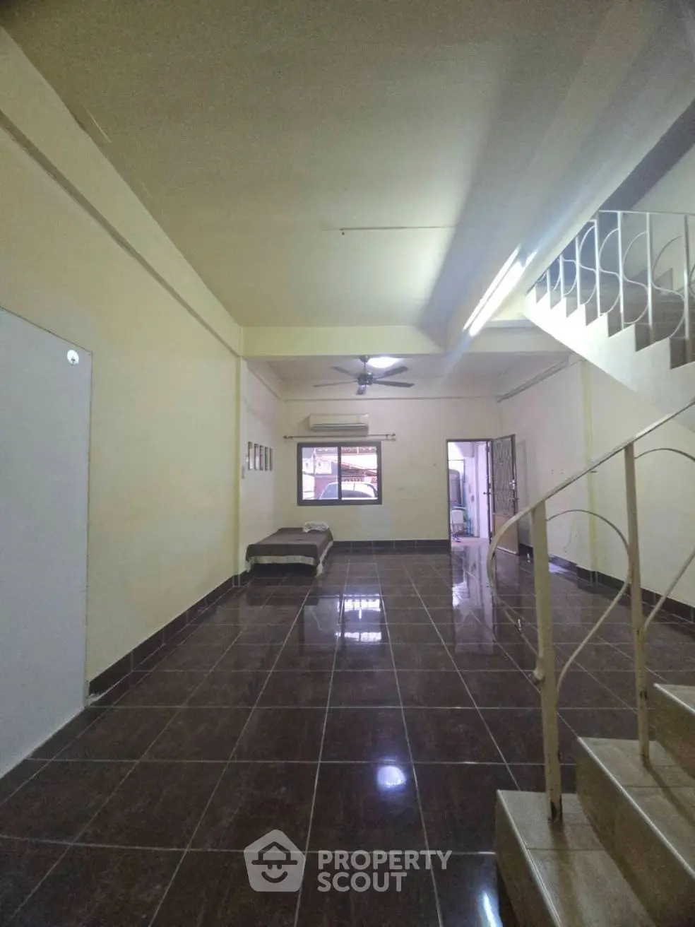 Spacious tiled living area with staircase and ceiling fan, ideal for modern living.
