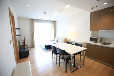 Modern open-plan living room with dining area and sleek kitchen in a bright apartment.