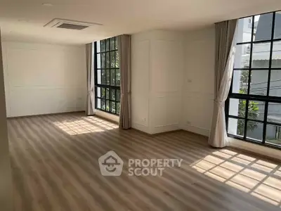 Spacious sunlit room with large windows and elegant flooring, perfect for modern living.