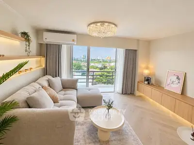 Elegant living room with plush sofa, chandelier, and balcony view in modern apartment.