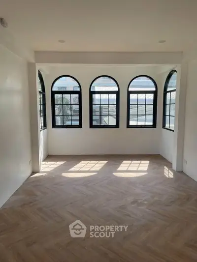 Spacious room with elegant arched windows and natural light, perfect for a stylish living area.