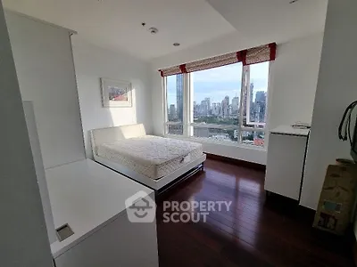 Spacious bedroom with city view and hardwood floors in modern apartment