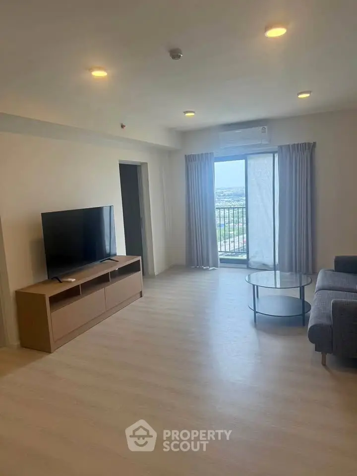 Spacious living room with modern furniture and balcony view in a high-rise apartment.