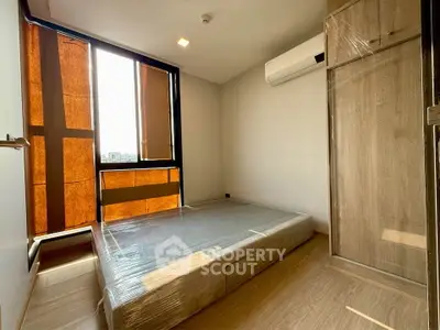Modern bedroom with wooden flooring, large window, and air conditioning unit.