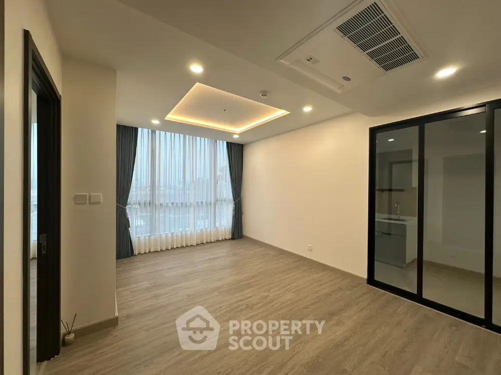 Spacious modern living room with large window and sleek flooring