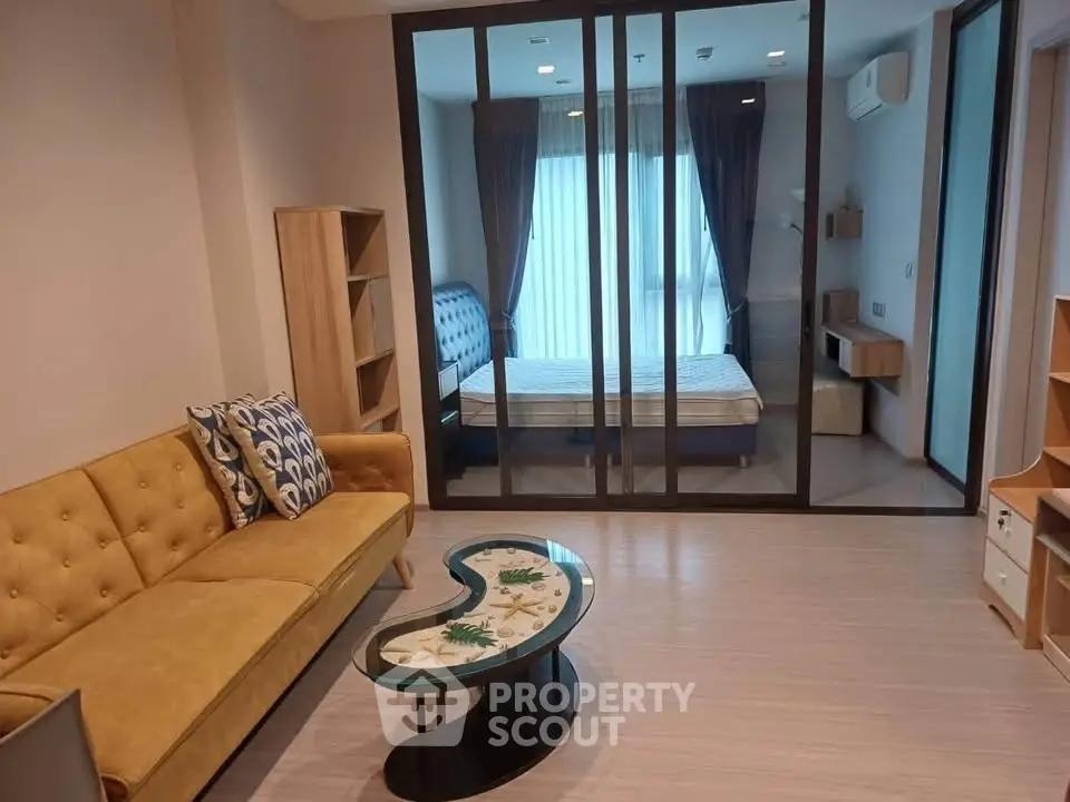 Modern living room with glass partition, stylish sofa, and cozy bedroom view.