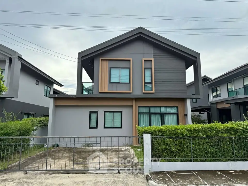 Modern two-story house with sleek design and large windows in a suburban neighborhood.