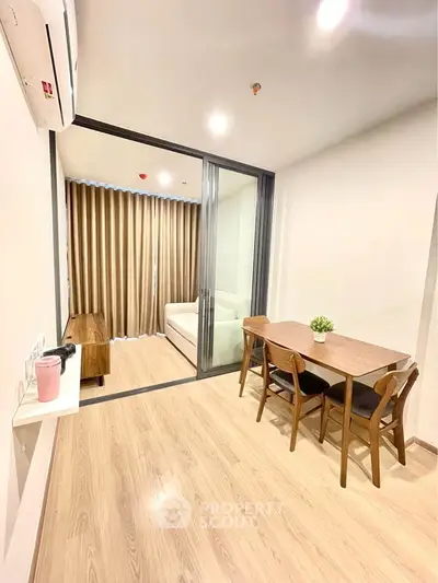Modern dining area with wooden table and chairs, adjacent to a cozy living room with a sofa and floor-to-ceiling curtains.