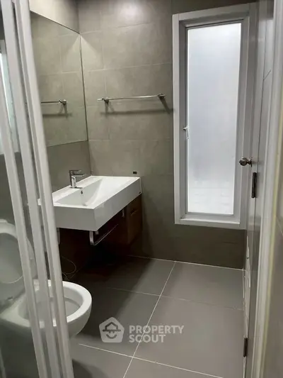 Modern bathroom with sleek fixtures and large frosted window for natural light.