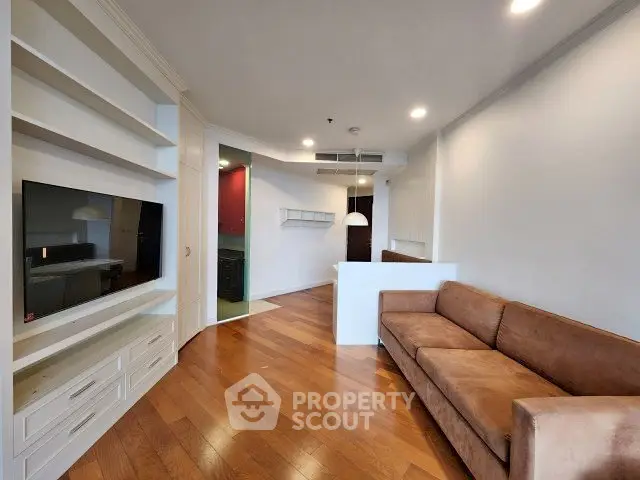 Spacious living room with built-in shelves and cozy brown sofa, perfect for relaxation.