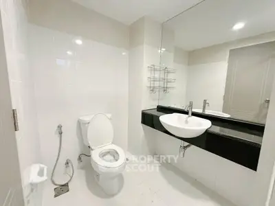 Modern bathroom with sleek fixtures and large mirror in a contemporary apartment.