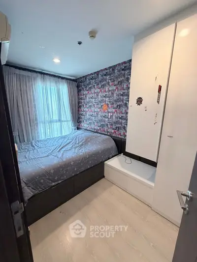 Cozy bedroom with modern decor and ample natural light, featuring stylish wallpaper and sleek flooring.