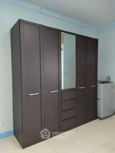 Spacious bedroom with sleek wardrobe and washing machine in modern apartment.
