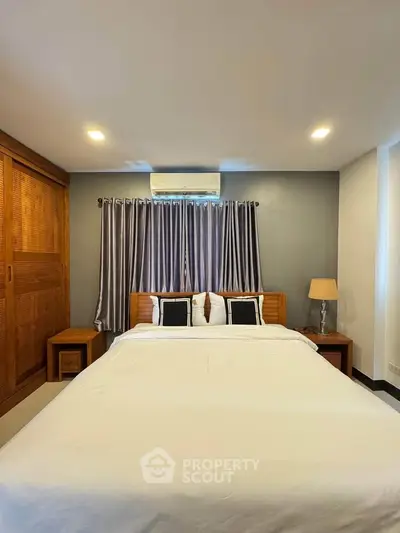 Cozy bedroom with wooden furniture and modern lighting, perfect for relaxation.