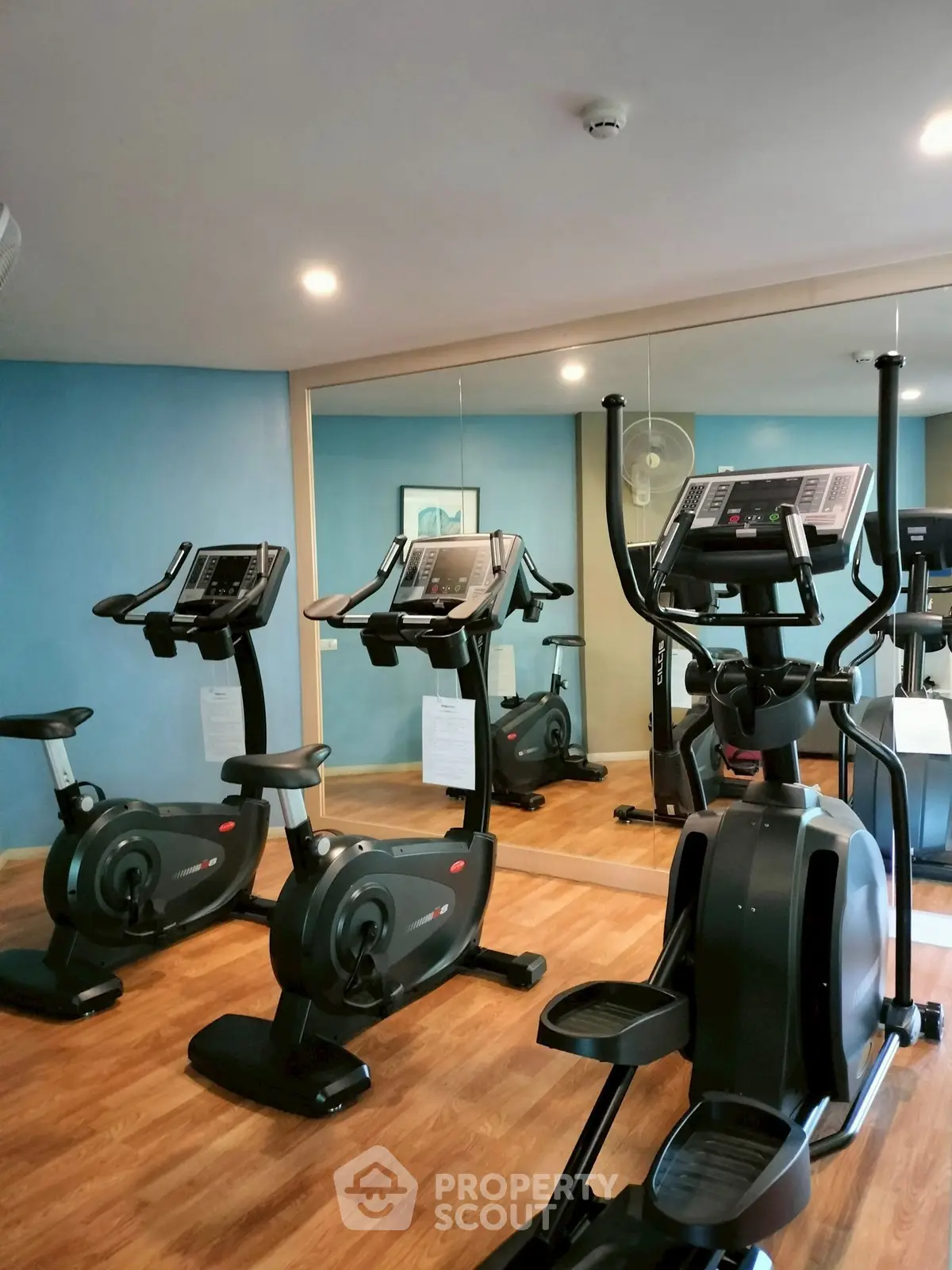 Modern gym with exercise bikes and mirrored walls in a residential building.