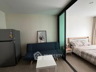 Modern studio apartment with cozy living area and bedroom separated by glass partition.