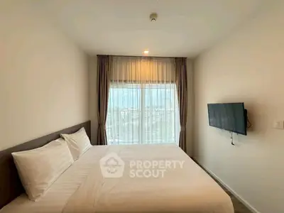 Modern bedroom with large window and wall-mounted TV in a stylish apartment.
