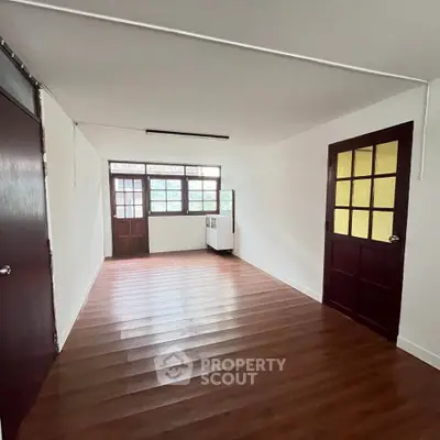 Spacious room with wooden flooring and large windows for natural light