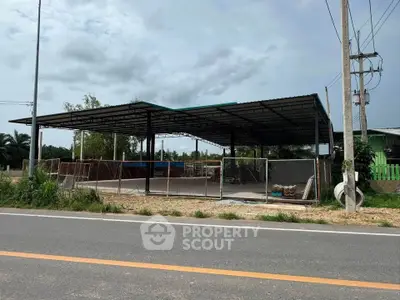 Spacious open-air structure with metal roof and fenced area, ideal for commercial use or storage.