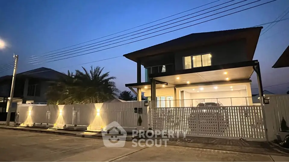 Stunning modern house exterior with illuminated fence and spacious driveway at dusk.