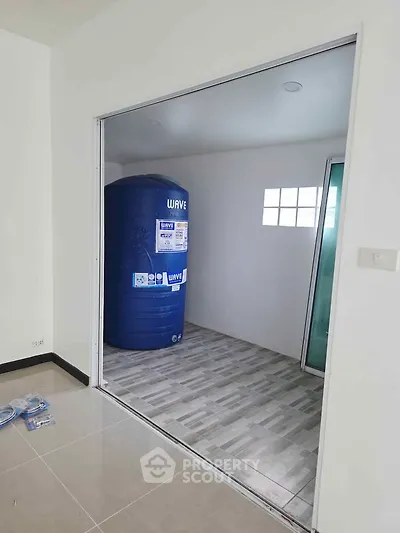 Spacious storage room with large blue water tank and tiled flooring