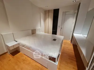 Modern bedroom with sleek design and wooden flooring, featuring a large bed and built-in storage.