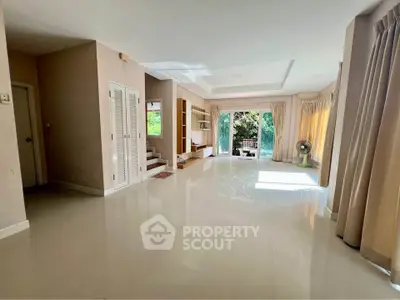 Spacious living room with large windows and garden view, perfect for family gatherings.
