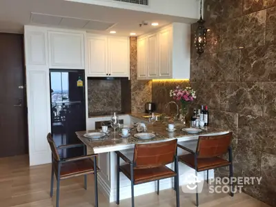 Elegant dining area seamlessly connects to a modern kitchen with white cabinetry and marble walls, perfect for entertaining guests.