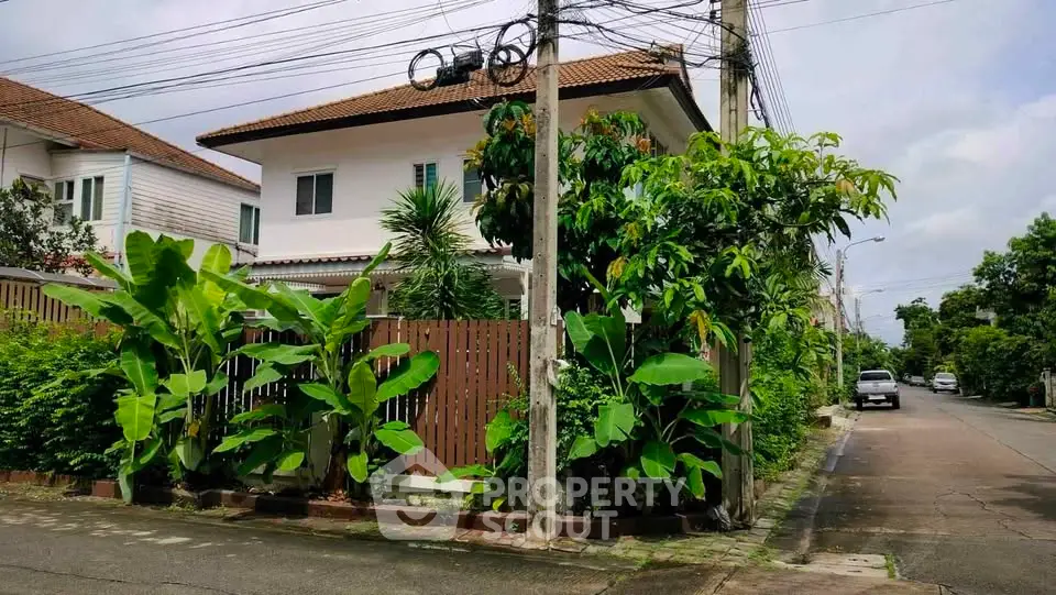 Charming suburban house with lush garden and privacy fence on a quiet street.