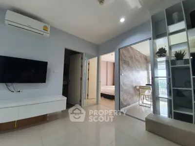 Modern living room with sleek design and open layout, featuring wall-mounted TV and air conditioning.