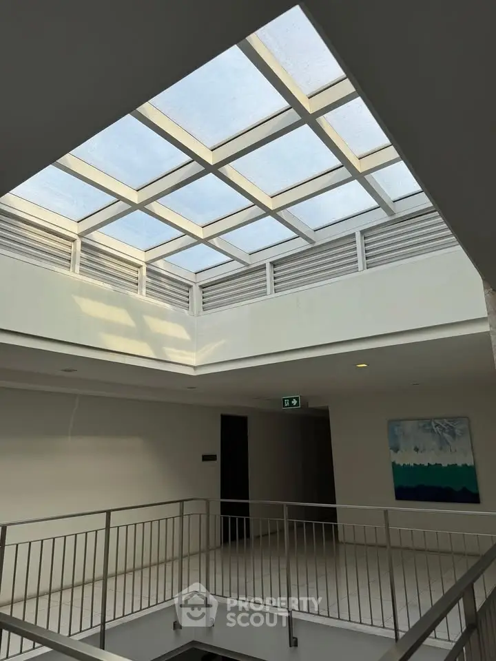 Modern building interior with skylight and railing, showcasing architectural design.