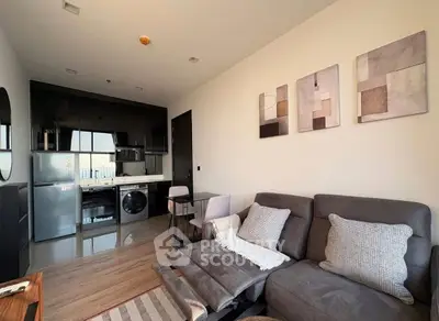 Modern living room with sleek kitchen, cozy seating, and stylish decor in a contemporary apartment.