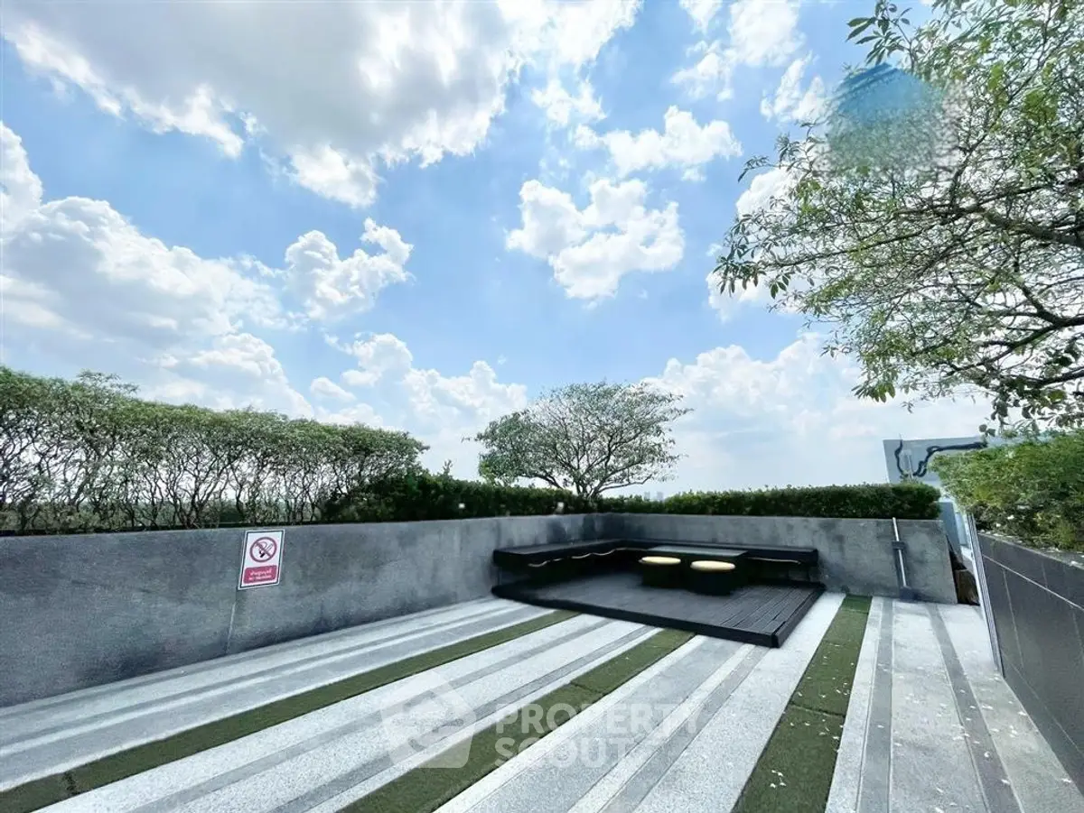 Stunning rooftop terrace with modern seating and lush greenery under a bright blue sky.